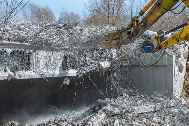 Professional demolition of reinforced concrete structures using industrial hydraulic hammer. Rods of metal fittings. Wreckage and crumbles of concrete.