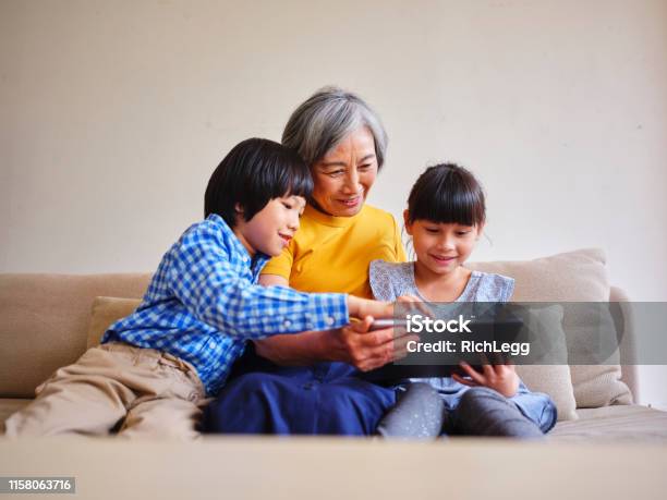 Grandmother Reading To Children In A Home In Taiwan Stock Photo - Download Image Now