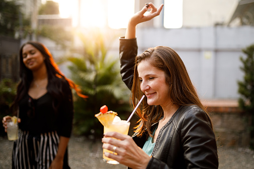 Friends having premium cocktails in a rooftop at sunset.