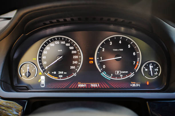 Electronic dashboard of modern luxury car with electronic display and with white arrows speedometer tachometer and other tools and icons.