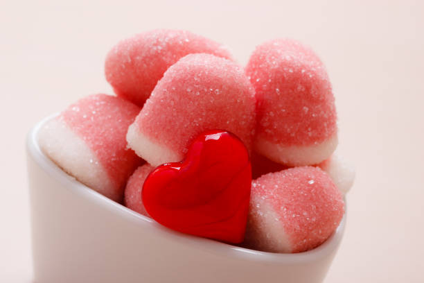 Sweet food candy. Pink jellies or marshmallows with sugar in white bowl on wooden table decorated with red heart love symbol