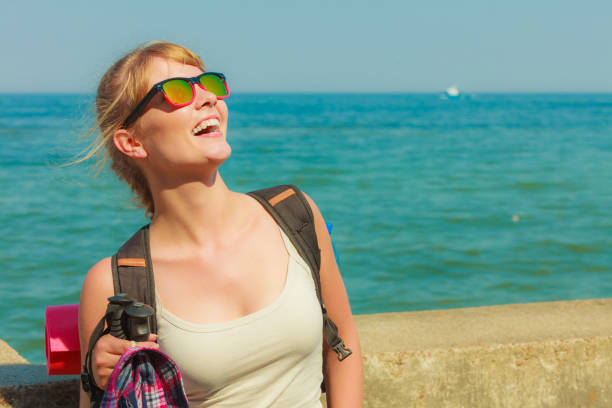 Adventure, tourism, enjoying summer time - young tourist woman with backpack hiking on sea coast