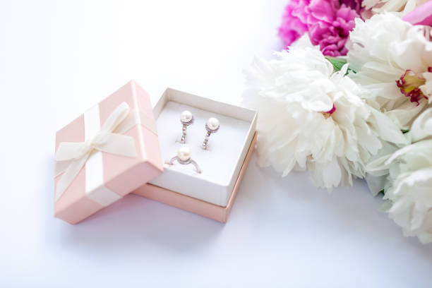 Set of silver ring and earrings with pearls in the gift box with peonies. Present for holiday stock photo