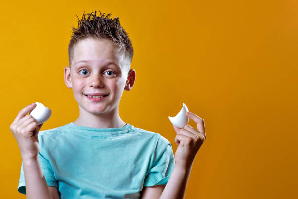 istock cheerful boy in a light t-shirt holding a broken egg on a colored background 1158071499