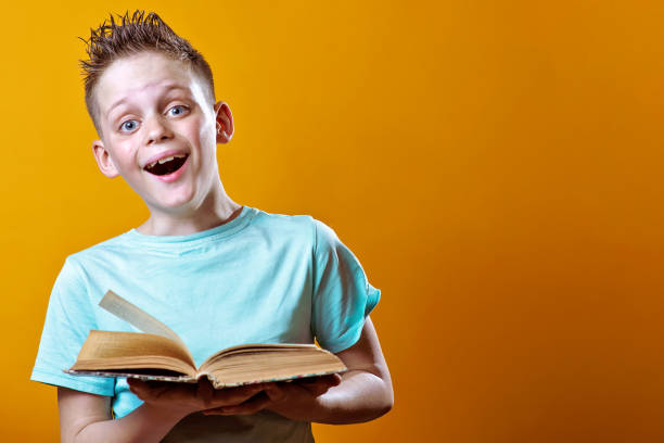 istock cheerful boy in a light t-shirt holding a book on a colored background 1158071502