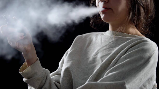 istock Woman exhaling vapor with electronic cigarette, device for smoking simulation 1158071801