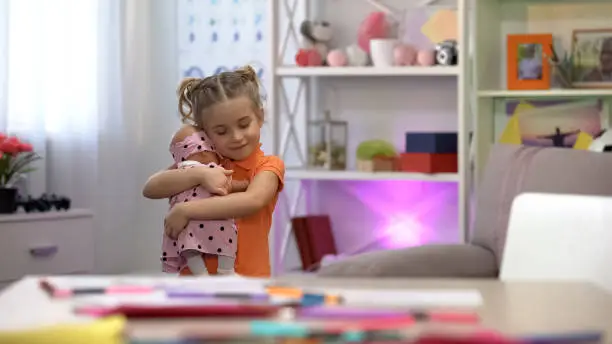 Photo of Girl holding doll, hugging favorite toy, girlish leisure, childhood happiness