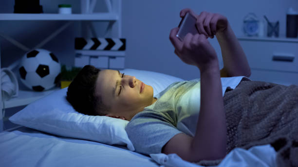 teenager watching video on smartphone, evening relaxation, gadget addiction - material data sheets imagens e fotografias de stock