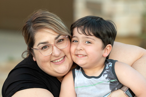Smiling hispanic mid adult woman posing with her son