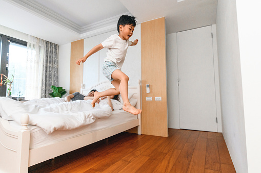 Energetic Taiwanese boys jumping off their parent's bed in the morning.