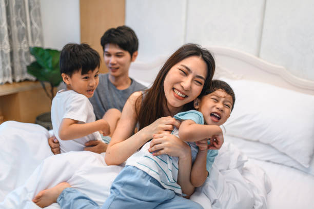 istock Young Taiwanese Parents Playing in Bed With Their Sons 1158086252