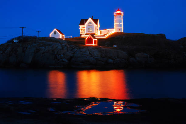 Christmas lights on the Nubble Lighthouse in York, Maine The Nubble Lighthouse, also known as teh Neddick Lighthouse in York Maine, is outlined in Christmas lights lighthouse lighting equipment reflection rock stock pictures, royalty-free photos & images