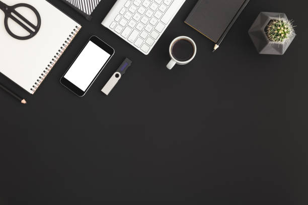 istock Black desk with mobile isolated, coffee and supplies. Top view. 1158090019