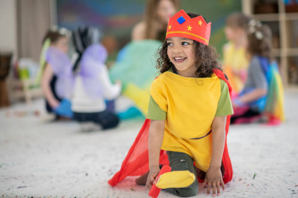 Boy dressed up in kings costume plays in a classroom A boy with long hair of Indian descent smiles as he sticks out his sword that goes along with his king's costume. He is on a carpet in a colourful elementary school classroom. acting stock pictures, royalty-free photos & images
