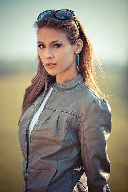 young woman in leather jacket and sunglasses outdoor portrait at sunset