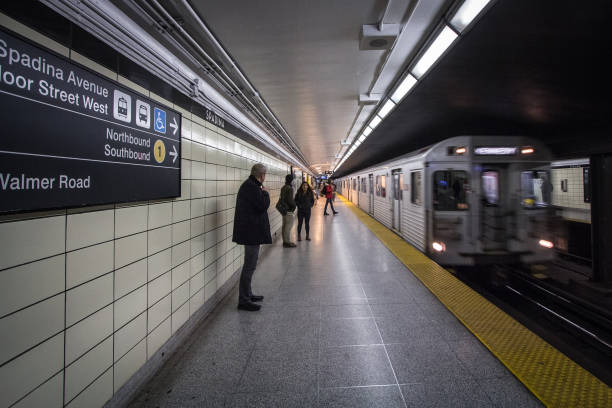 les gens attendent un métro dans le quai de la gare spadina, tandis qu'un train de métro exploité par la ttc, toronto transit commission, arrive, avec un flou de vitesse. - ttc photos et images de collection