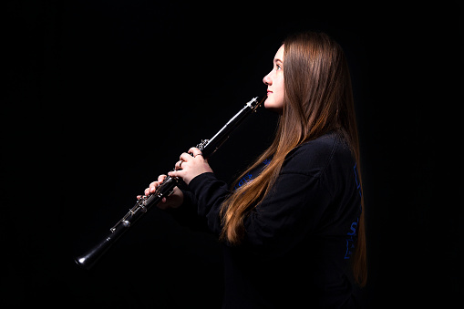 A teenage girl playing her clarinet for the High School band.