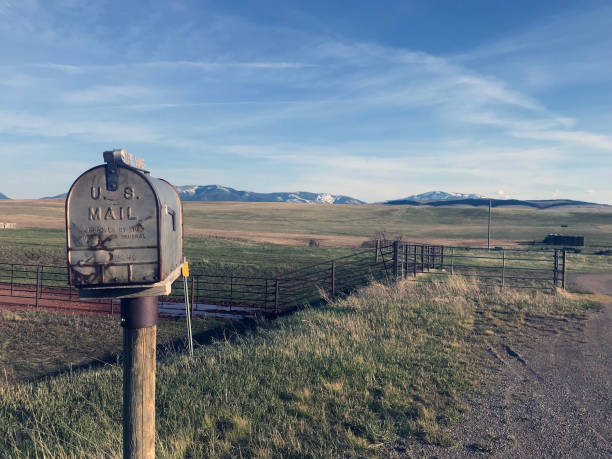 A large mailbox with the flag down along a gravel road.