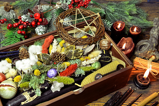 Wicca concept with box of presents, black candles, pentagram, magic healing herbs, conifer.