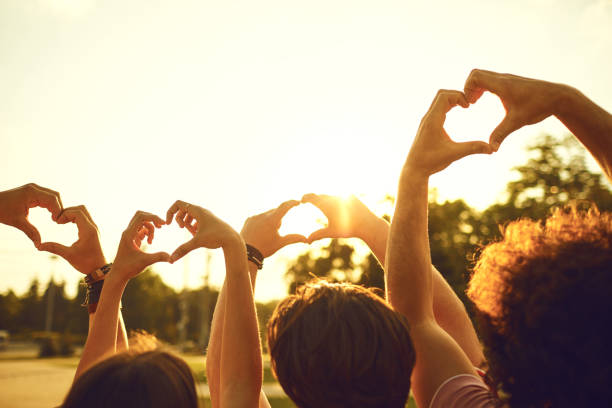 руки групповых друзей в форме сердца на фоне заката. - sunny season summer autumn стоковые фото и и�зображения