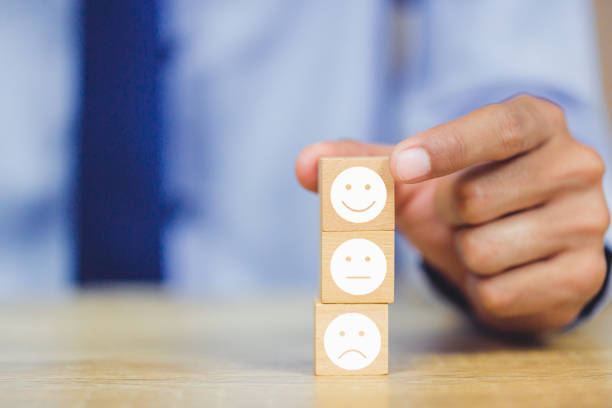 istock customer pressing smiley face emoticon on wood cube, Service rating, satisfaction concept. 1158126610