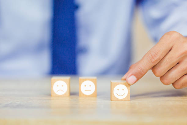 istock customer pressing smiley face emoticon on wood cube, Service rating, satisfaction concept. 1158126631