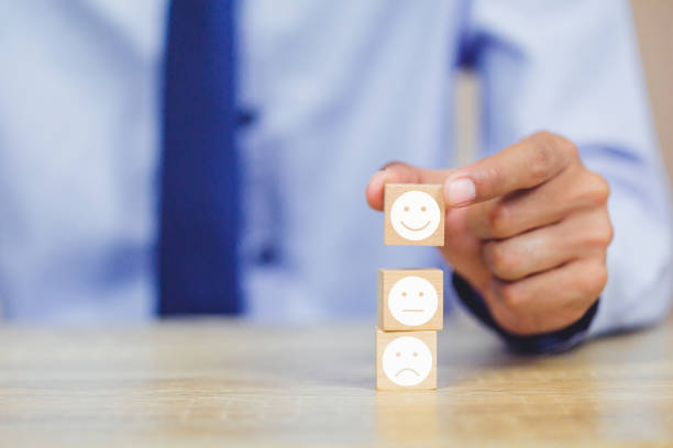 istock customer pressing smiley face emoticon on wood cube, Service rating, satisfaction concept. 1158126635