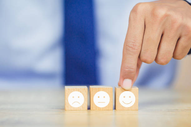 istock customer pressing smiley face emoticon on wood cube, Service rating, satisfaction concept. 1158126654