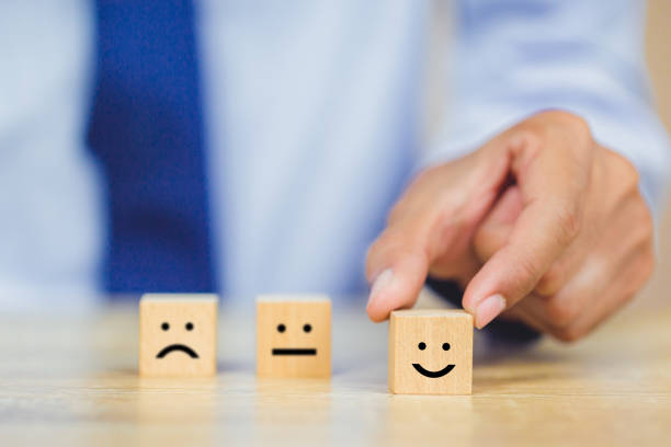 istock customer pressing smiley face emoticon on wood cube, Service rating, satisfaction concept. 1158126757