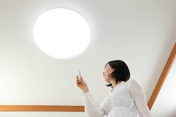 Lighting & Women Young Asian women pressed the light switch ceiling lamp stock pictures, royalty-free photos & images