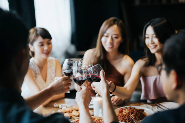 Group of joyful young Asian man and woman having fun and toasting with red wine during party Group of joyful young Asian man and woman having fun and toasting with red wine during party blind date stock pictures, royalty-free photos & images