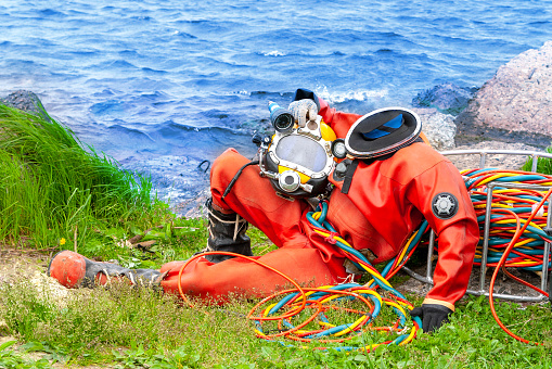 Diver in an orange suit sitting on the shore. Template for photoshop.