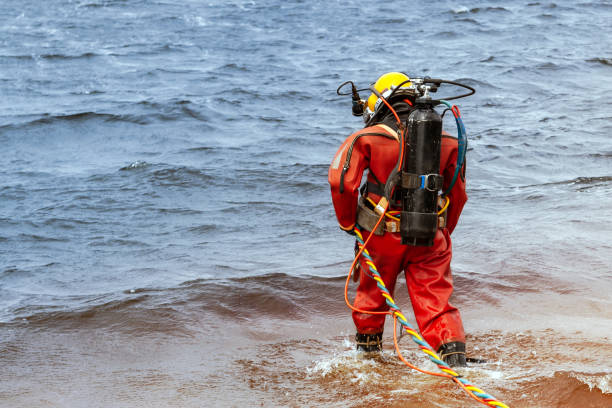 Professional diver enters the water to produce deep-sea works. A professional diver in an orange wetsuit enters the water for deep-sea work. diving sport stock pictures, royalty-free photos & images