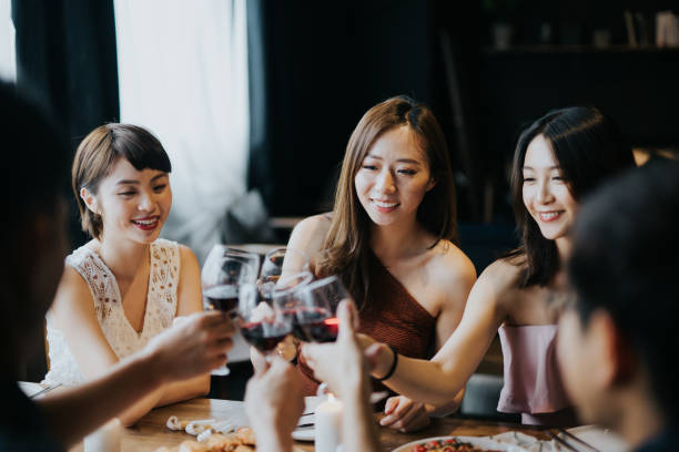 Group of joyful young Asian man and woman having fun and toasting with red wine during party Group of joyful young Asian man and woman having fun and toasting with red wine during party blind date stock pictures, royalty-free photos & images