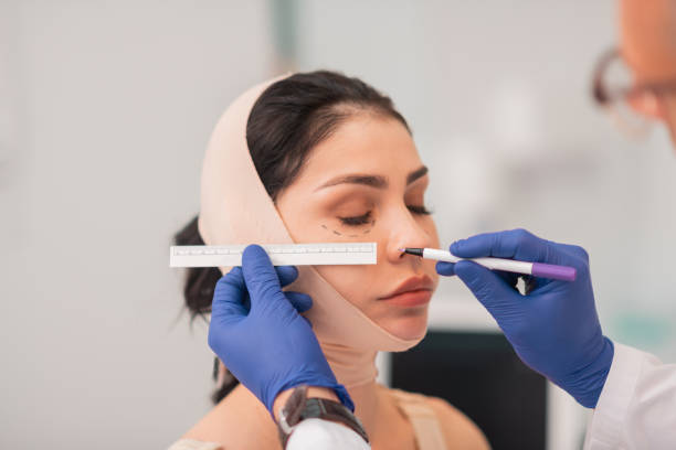 istock Plastic surgeon wearing blue gloves making face measurements 1158130836