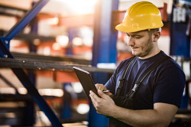 istock Mid adult manual worker using touchpad in aluminum mill. 1158140211
