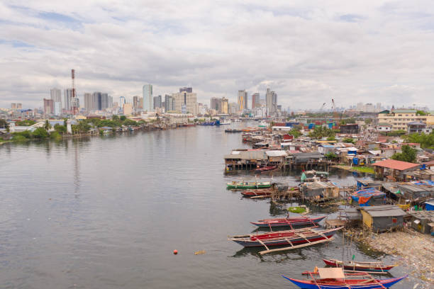 manila baraccopoli sullo sfondo di una grande città. case e barche dei poveri abitanti di manila. contrasto degli strati sociali - manila apartment poverty slum foto e immagini stock