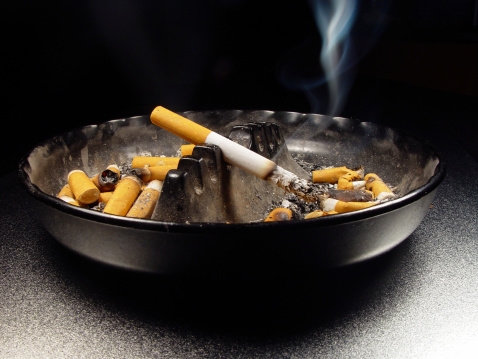 detailed image of cigarette in ashtray with visible smoke.  Although the image has a dark background, the boundry lines are pretty clear so the ashtray can be cut out of the photo if you need a white background.