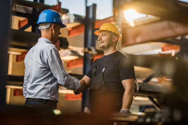 istock Happy metal worker shaking hands with a manager in a warehouse. 1158144910
