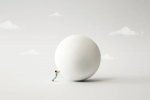 istock man rolling big heavy ball, surreal concept 1158149431