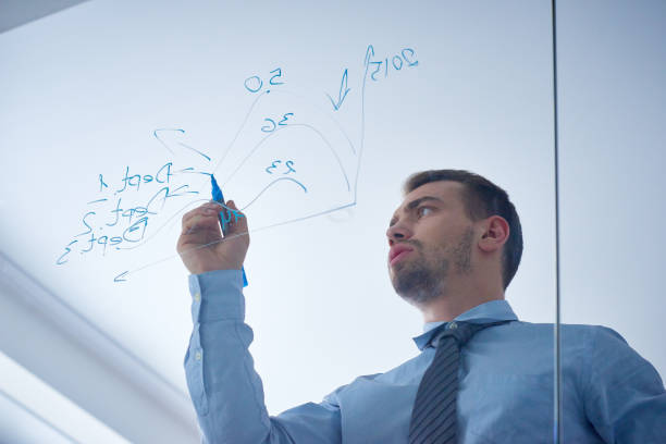 istock Serious businessman making accounting on glass wall 1158149507