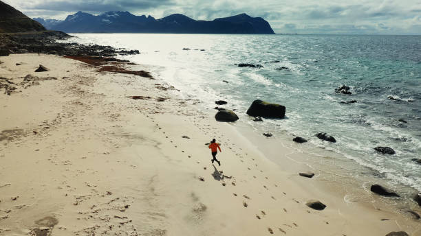 istock Aerial drone view: man running in Lofoten Islands 1158156388