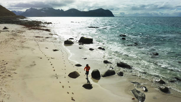 istock Aerial drone view: man running in Lofoten Islands 1158156391