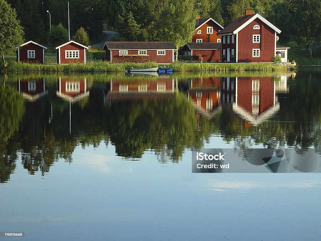 red painted Swedish lakeside houses reflection Swedish lakeside on a warm and calm summer evening with typical red painted Swedish houses reflecting in the water House Stock Photo