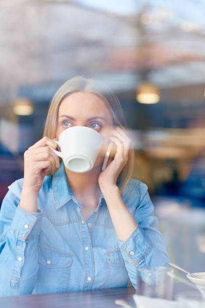 istock Woman drinking and talking on phone in cafe 1158156825
