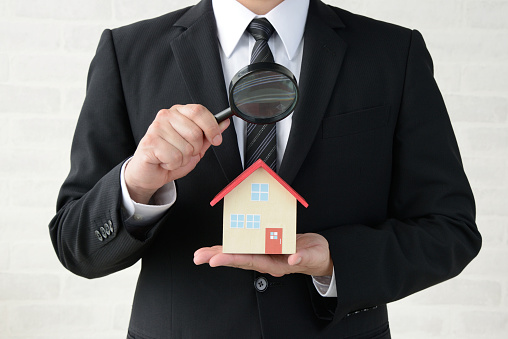 Business man inspecting house with magnifying glass