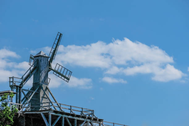 The stark silhouette of a traditional windmill stands out against the dramatic cloudscape, evoking the rural history within Potsdam's evolving landscape.