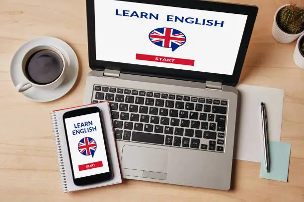 Learn English concept on laptop and smartphone screen over wooden table. Flat lay
