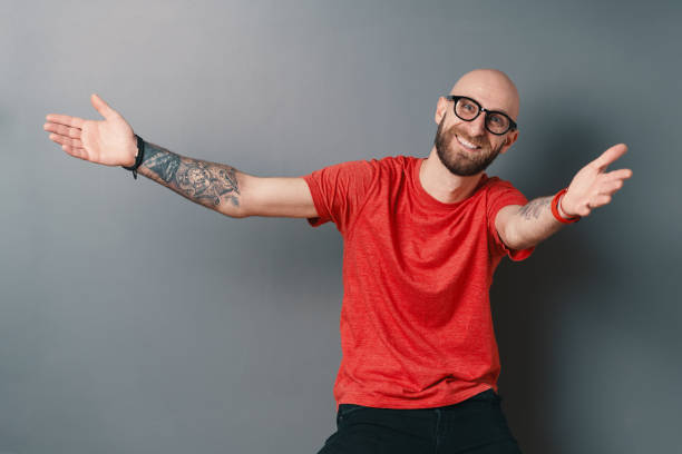 istock You are always welcome! Man with glasses gesturing and smiling while standing against grey background 1158169390