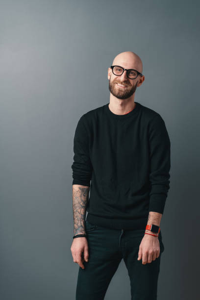 istock Young smiling man with beard and glasses on gray studio background 1158169396